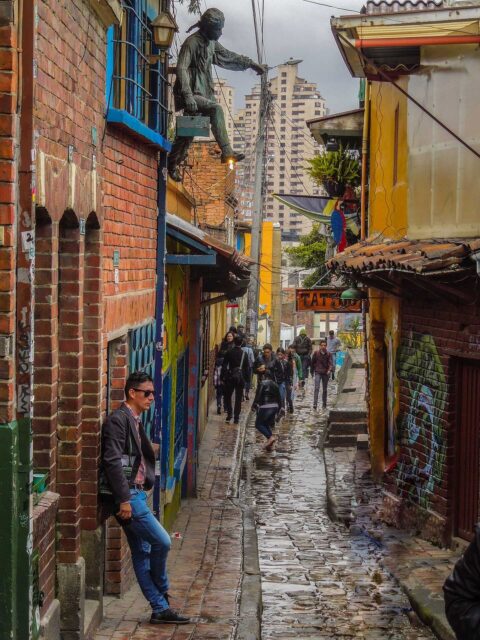 Things to Visit in Bogota: A vibrant street view of La Candelaria, the famous historic neighborhood in Bogotá, Colombia, featuring colorful buildings and street art.