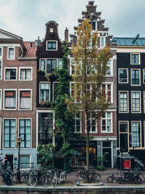 Places to stay Amsterdam: Classic canal-side buildings in Centrum (City Center) with parked bicycles, showcasing the charming architecture of Amsterdam.
