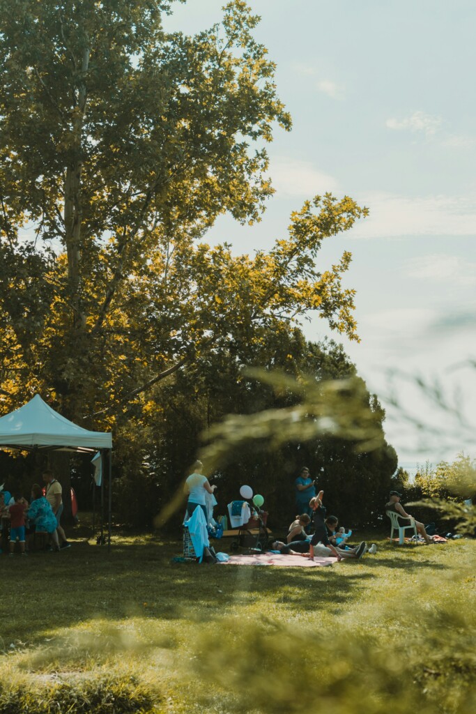 A group of people enjoying a sunny day at a campsite, with a tent, canopy, and picnic setup—perfect for those searching for tent camping near me and family-friendly camping spots.