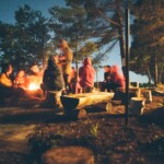 A group of friends gathered around a campfire at night, sharing stories and enjoying the outdoor experience.